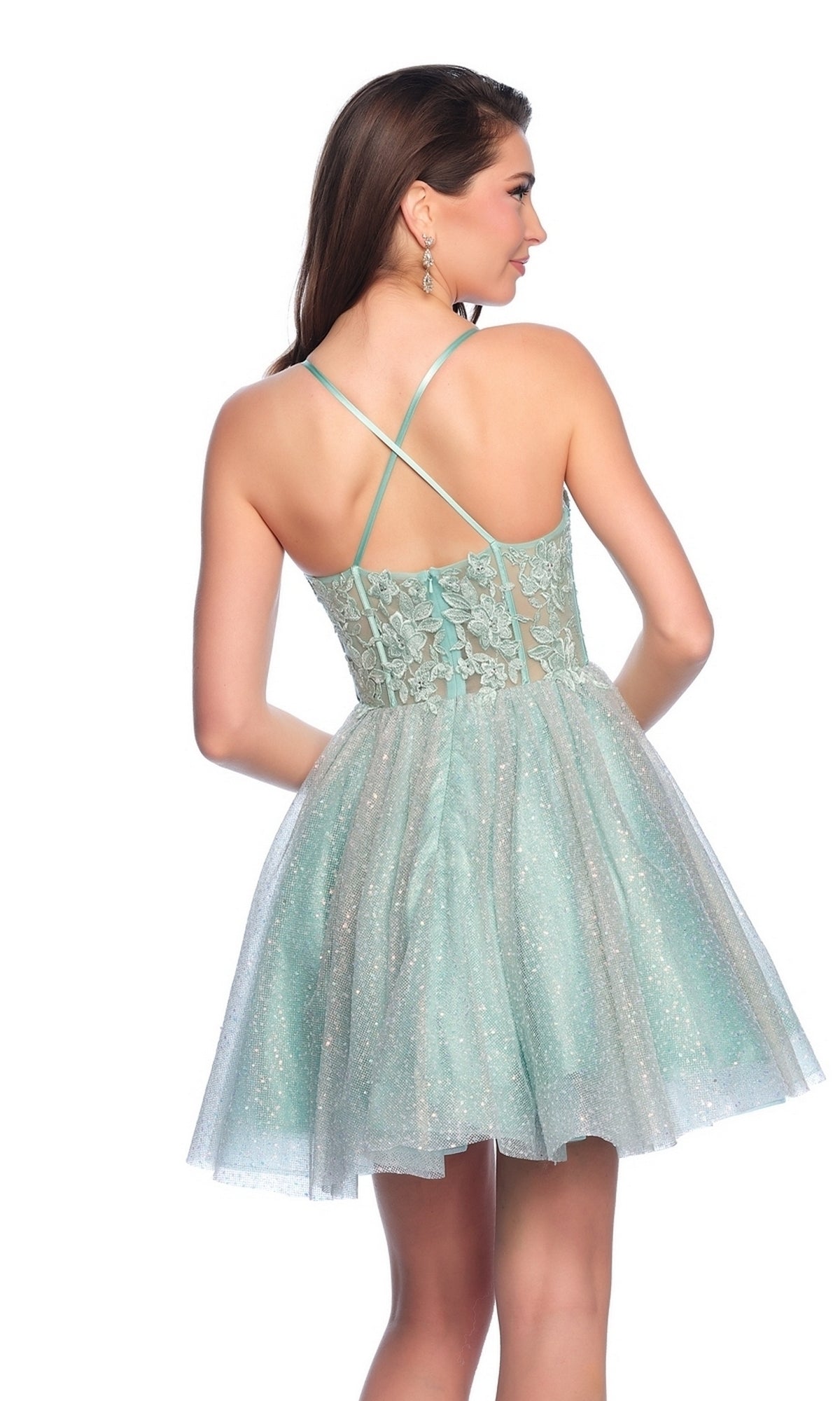 A woman poses with her back to the camera in the Dave & Johnny Short Glitter Hoco Dress 11808, a light blue homecoming dress featuring lace details and crisscross straps.